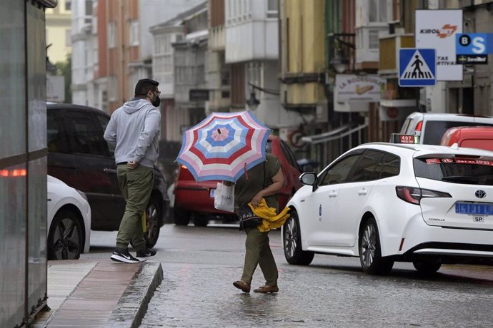 Archivo - Una mujer se resguarda del viento y la lluvia con un paraguas en el centro de la ciudad, a 19 de junio de 2022, en A Coruña, Galicia, (España). 