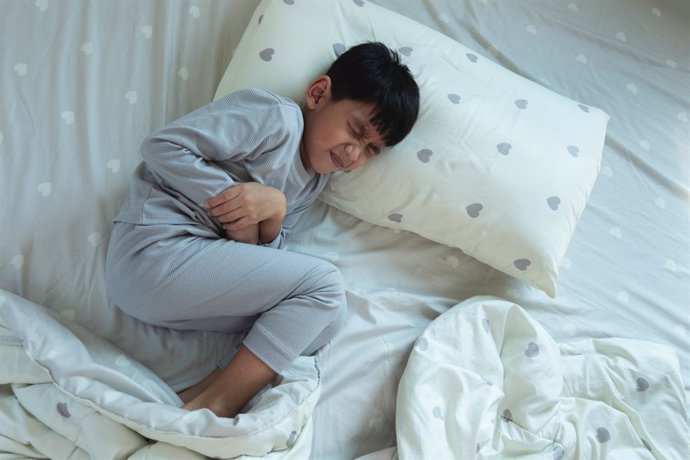 Archivo - Vista superior de un niño costado en la cama con dolor de estómago