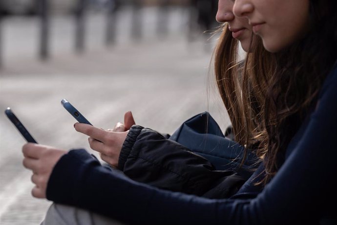 Archivo - Dos personas usan el teléfono móvil, a 1 de febrero de 2024, en Barcelona, Catalunya (España). El pasado 30 de enero el Govern aprobó las instrucciones que regulan el uso de los dispositivos móviles en las aulas de colegios e institutos