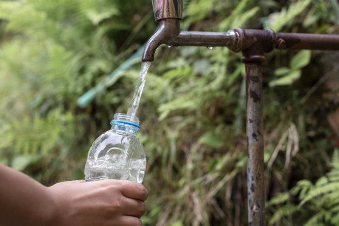 Archivo - Llenando una botella de agua en un grifo.