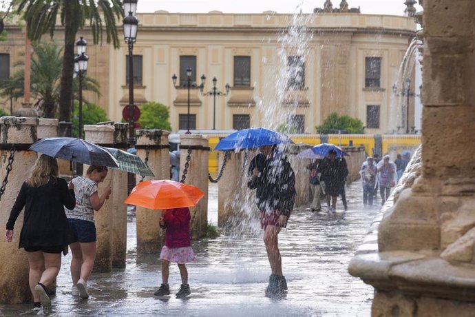 Archivo - Transeúntes protegidos con paraguas de la lluvia en Sevilla, imagen de archivo. 