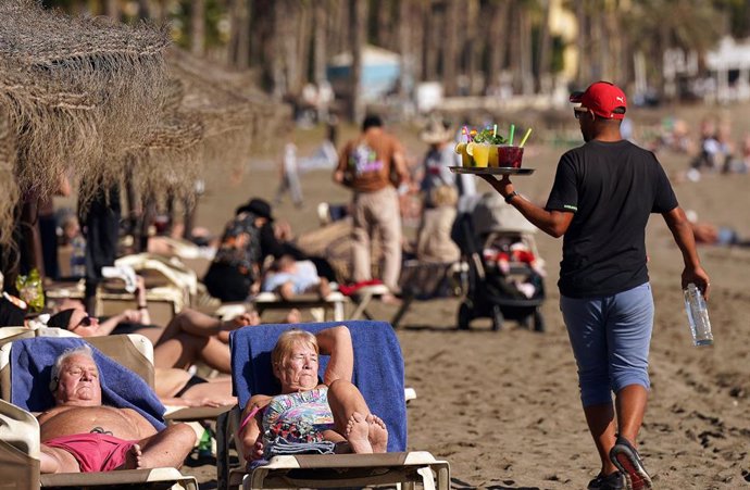 Archivo - Varias personas disfrutan tomando el sol en la playa de la Malagueta.