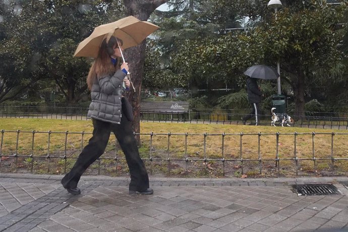 Archivo - Una mujer se protege de la lluvia con un paraguas durante la borrasca ‘Karlotta’, a 9 de febrero de 2024, en Madrid (España). 