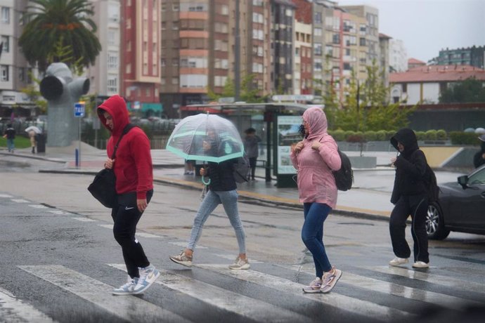 Archivo - Varias personas se cubren de la lluvia y el viento con paraguas.- Archivo