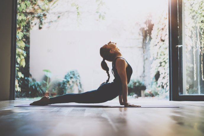 Archivo - Portrait of gorgeous young woman practicing yoga indoor. Beautiful girl practice cobra asana in class.Calmness and relax, female happiness.Horizontal, blurred background.Visual effects.