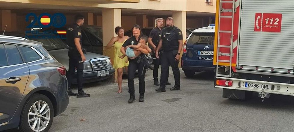 Una policía saca en brazos a uno de los menores involucrados en el incendio de una vivienda de Alcalá.