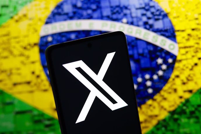 El logo de la red social X en un teléfono móvil frente a la bandera de Brasil (archivo)