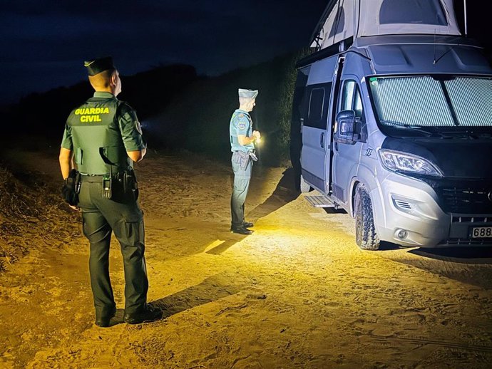 Agentes de la Guardia Civil junto a una de las autocaravanas desalojadas en Tarifa (Cádiz)