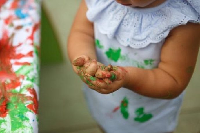 Las manos de una niña llenas de pintura. 