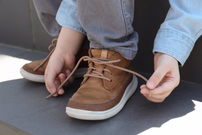 Archivo - Niño atándose los cordones de las zapatillas