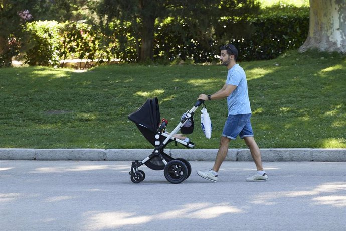 Archivo - Un hombre pasea con un carrito de bebé en el parque de El Retiro.