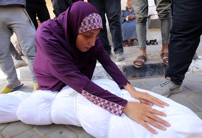 Una mujer junto a un cadáver de un palestino fallecido en la Franja de Gaza