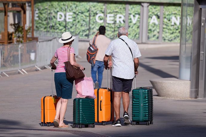 Dos señores mayores esperan con sus maletas en una calle de Madrid, a 28 de agosto de 2024, en Madrid (España).  