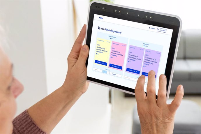 Archivo - Senior woman at home standing at kitchen holding digital tablet controlling smart home system back view checking cameras close-up.