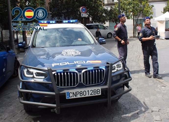 Dos agentes de Policía Nacional junto a un coche patrulla