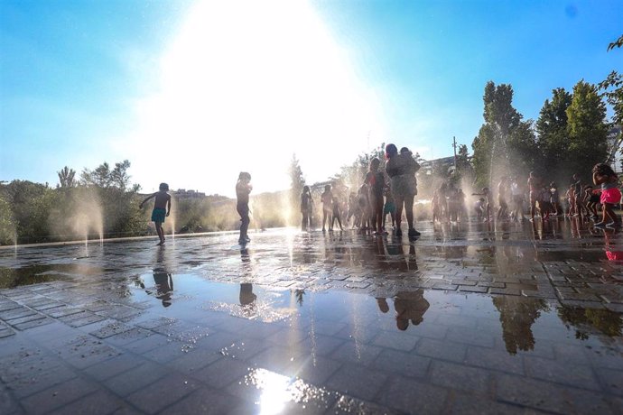 Archivo - Varios niños se refrescan en una fuente durante la tercera ola de calor en Madrid, en el parque Madrid Río