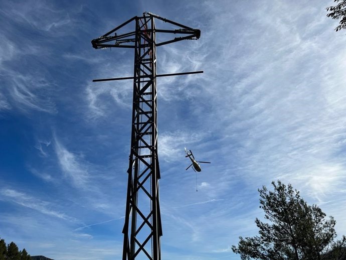 Archivo - Un helicóptero sobrevuela una de las torres de suministro eléctrico restablecidas en Mallorca.