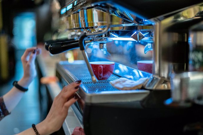 Archivo - Una trabajadora prepara un café en un establecimiento de hostelería.