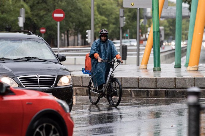 Archivo - Un repartidor trabaja bajo la lluvia.