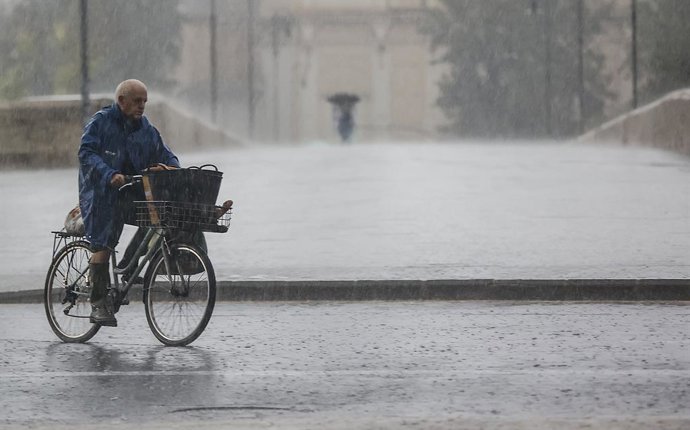 Archivo - Arxiu - Una persona amb bicicleta baix la pluja a Valncia