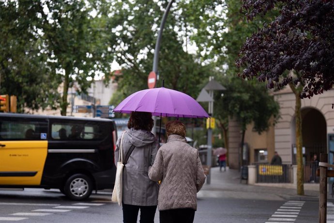 Archivo - Varias personas con paraguas pasean por una de las calles de la ciudad, a 12 de mayo de 2023, en Barcelona, Catalunya