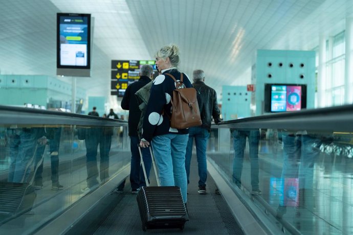 Archivo - Una mujer camina con su maleta en una cita en un aeropuerto.