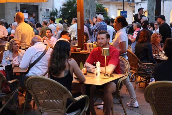 Archivo - Varias personas en una terraza durante una manifestación contra la masificación turística.