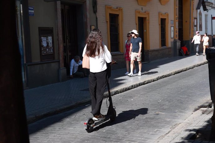 Una joven circula en un patinete eléctrico en una calle del centro de Sevilla. A 7 de agosto de 2024, en Sevilla (Andalucía, España).