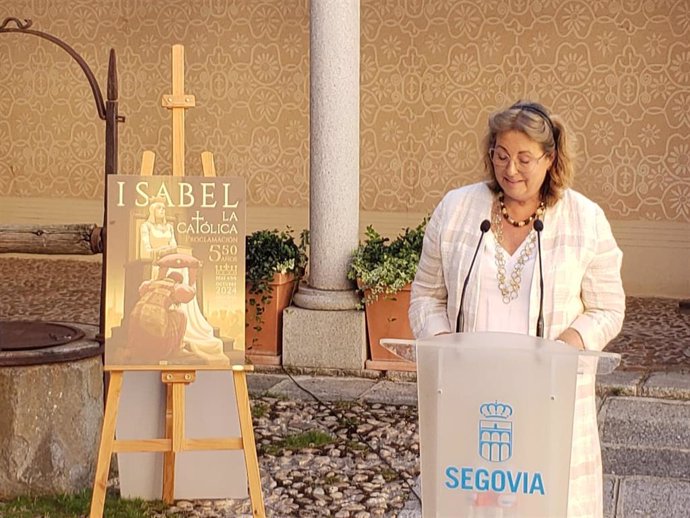 La concejal de Turismo de Segovia, May Escobar, enumera los actos del programa ante el cartel anunciador del evento