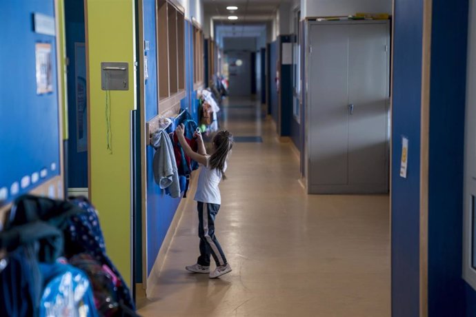 Archivo - Una niña cuelga su mochila en un perchero antes de entrar en clase.