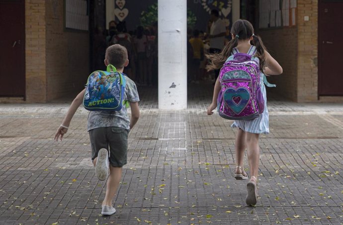 Archivo - Dos estudiantes llegan a un colegio.