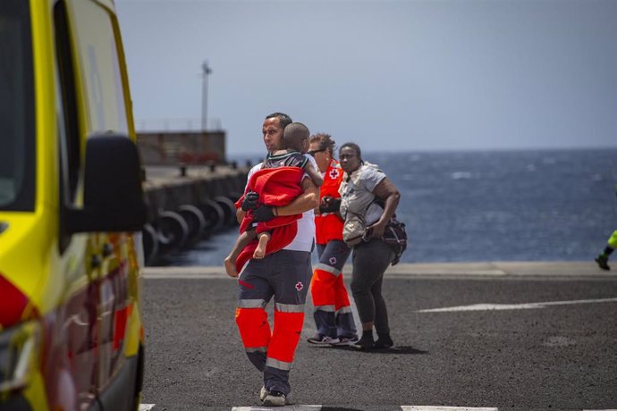 Un miembro de Salvamento Marítimo coge en brazos a un bebé migrante a su llegada al  puerto de La Restinga