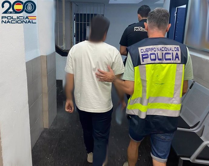 Uno de los detenidos, conducido por agentes en dependencias policiales.