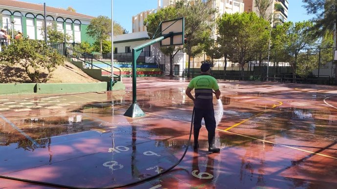 Un operario realiza trabajos de limpieza en el patio de un centro educativo.