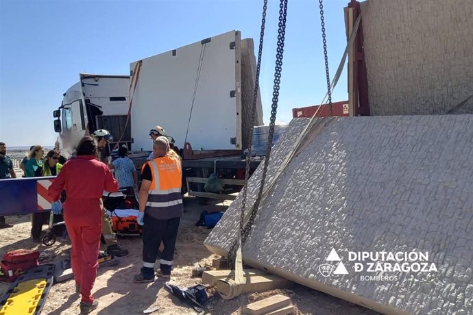 Bomberos y personal de Protección Civil en Quinto, donde un trabajador había quedado atrapado por las piernas por un bloque de hormigón despredido de su camión.