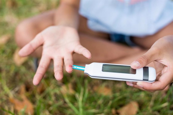 Archivo - Girl testing diabetes on glucose meter in park