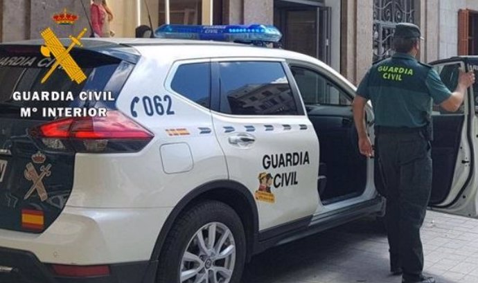 Archivo - Un agente y un coche de la Guardia Civil.