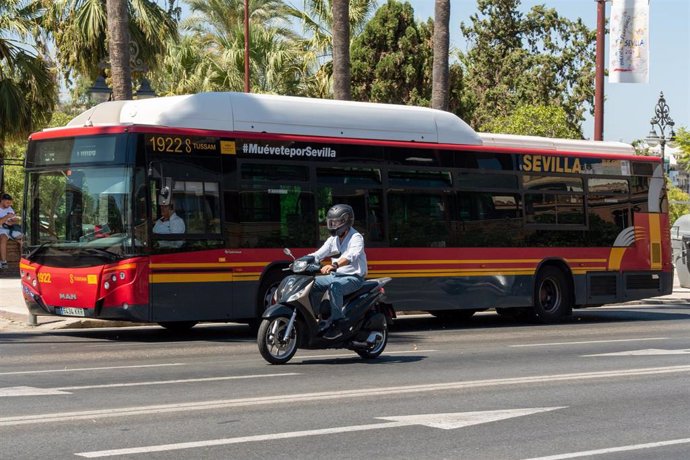 Una motocicleta circula junto a un autobús de Tussam en el Paseo de Colón. Imagen de archivo.