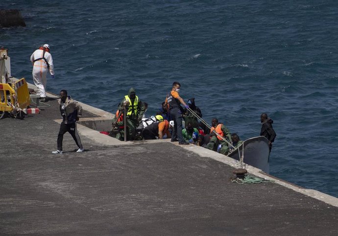 Migrantes bajan de un cayuco a su llegada al puerto de La Restinga