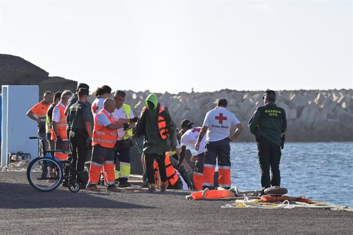 Archivo - Varios emigrantes son atendidos a su llegada a un muelle de Canarias