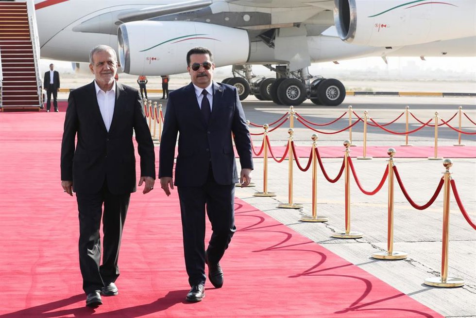 El primer ministro de Irak, Mohamad Shia al Sudani (d), recibe en el aeropuerto de Bagdad al presidente de Irán, Masud Pezeshkian (i)