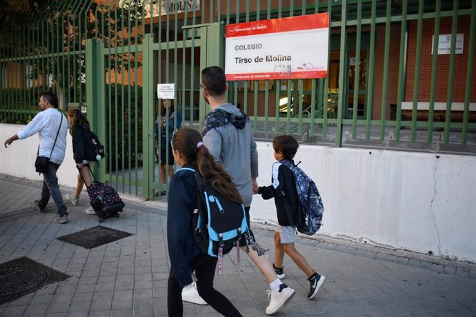 Un padre con sus hijos el primer día de colegio.