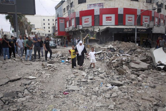 Una familia palestina junto a los restos de edificios destruidos en Jenín por ataques de las Fuerzas de Defensa de Israel (FDI)