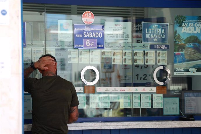 Archivo - Una persona se dispone a adquirir un boleto en una Administración de Loterias, en el centro de Sevilla.