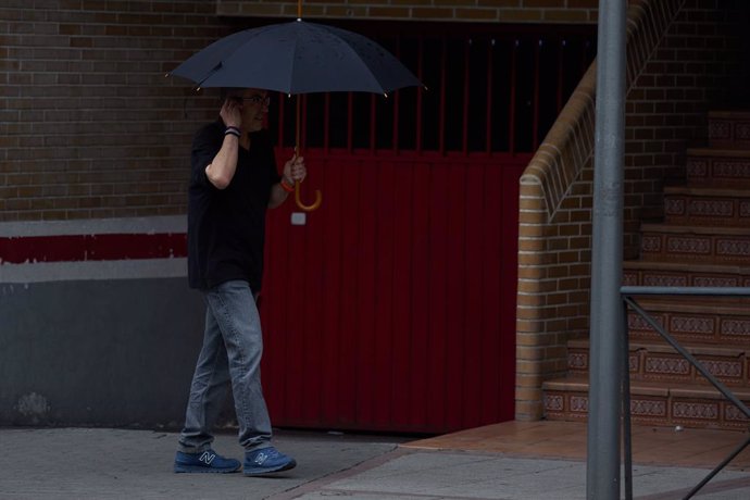 Archivo - Un hombre se protege de la lluvia con un paraguas, a 8 de junio de 2024, en Madrid (España). 