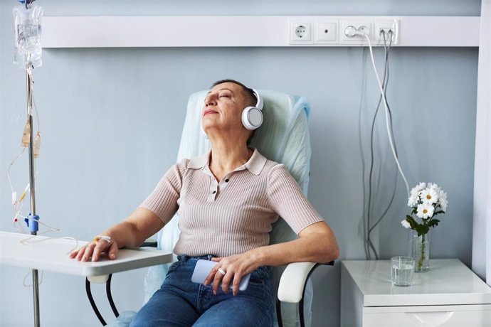 Archivo - Portrait of senior woman using relaxing with headphones during IV drip treatment in hospital