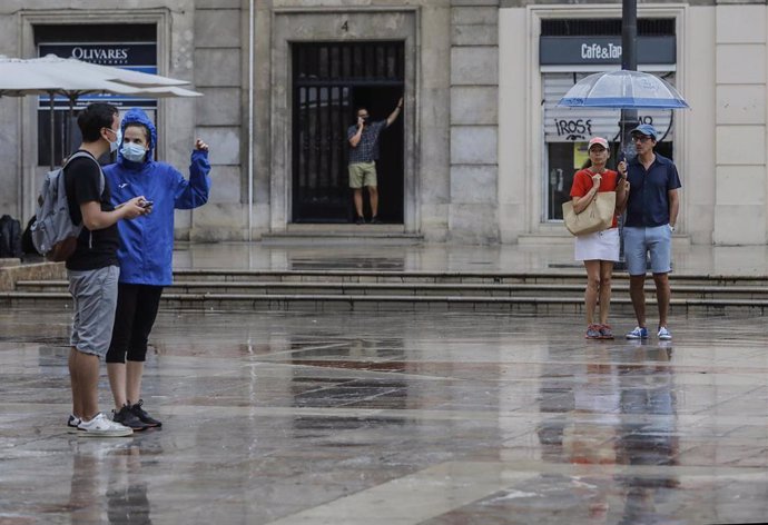 Archivo - Varias personas sostienen un paraguas mientras llueve