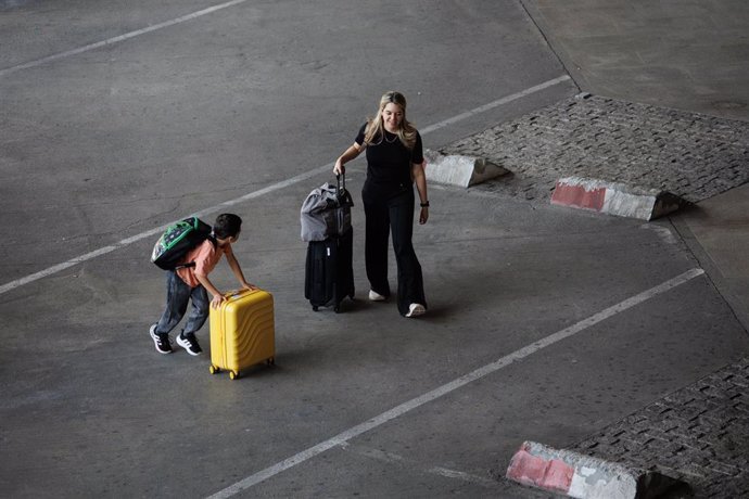 Archivo - Una mujer y un niño llegan a la terminal de un aeropuerto.