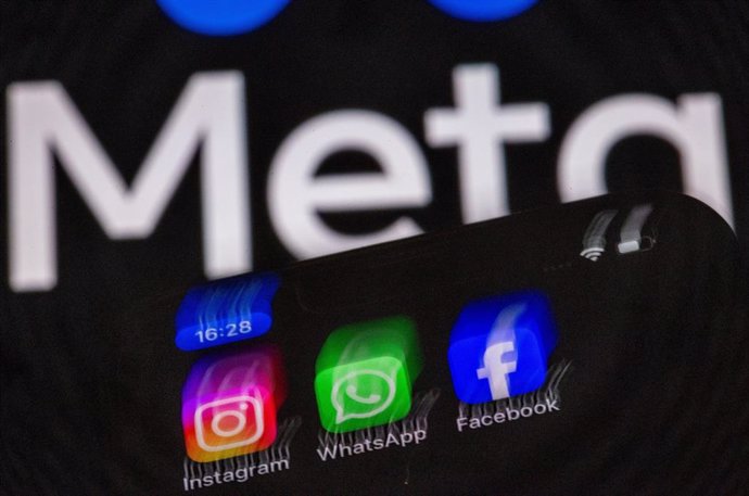 Archivo - Fotografía de archivo de los logos de Instagram, Facebook y WhatsApp en un teléfono móvil, con el logo de Meta de fondo