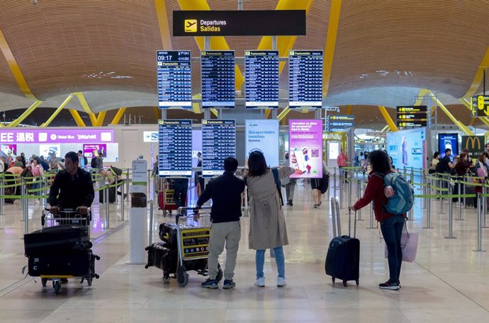Archivo - Un grupo de personas frente al panel del orden de vuelos en la terminal T4 del aeropuerto de Adolfo Suárez-Madrid Barajas, a 28 de abril de 2023, en Madrid (España). La red de aeropuertos de Aena prevé operar un total de 28.373 vuelos en este pu
